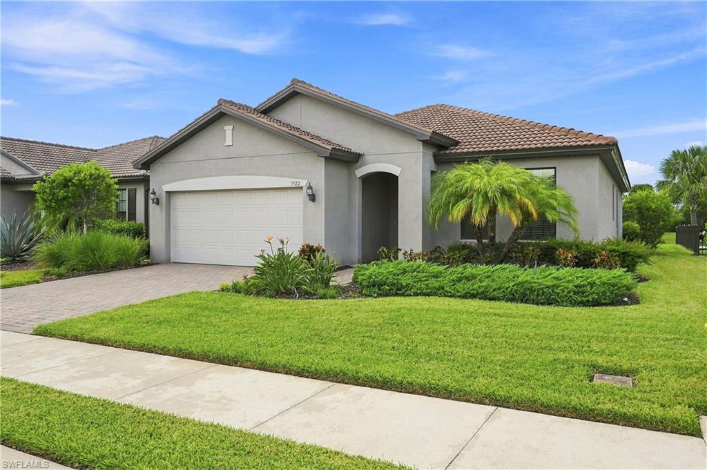 Smooth stucco exterior with a tiled roof, paver driveway, and an attached garage