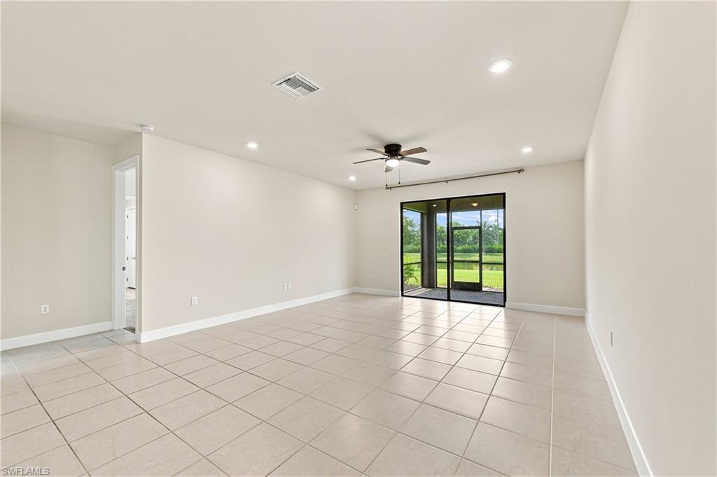 Expansive room featuring tile flooring, a dark-toned ceiling fan, recessed lighting, and sliding glass doors leading to a screened outdoor area