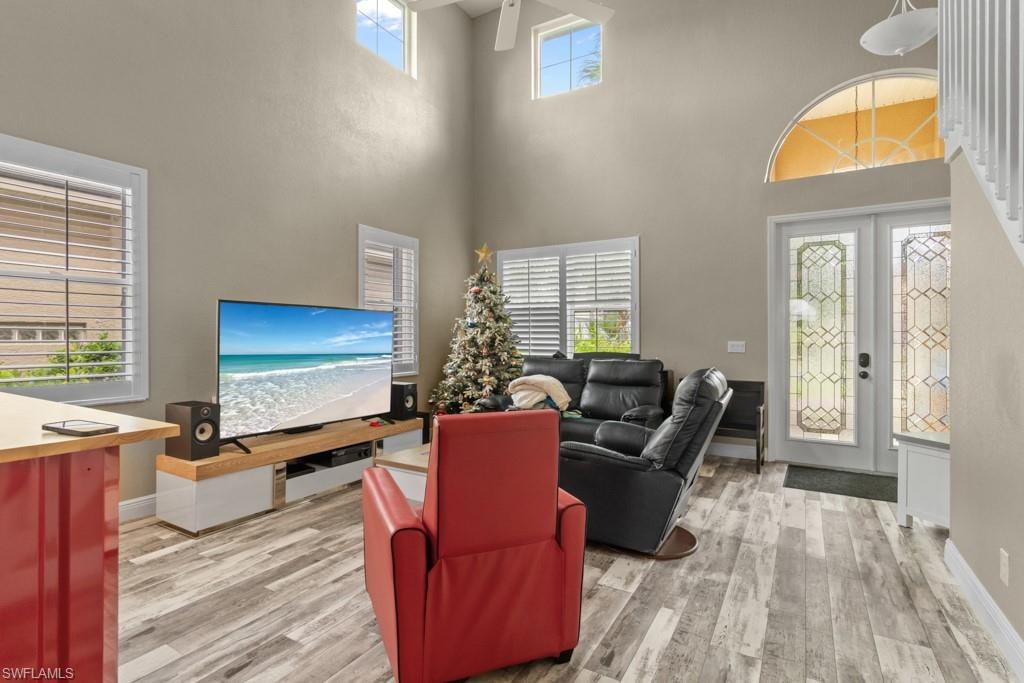 Soaring two-story great room with abundant natural light from multiple windows and glass doors, complemented by a decorative arched transom