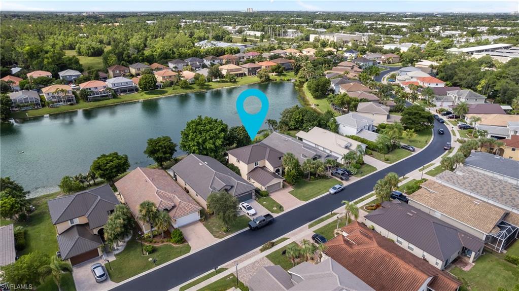 Residential property with a water feature, multiple homes, paved street, and mature landscaping