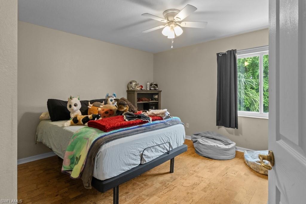 Bright secondary bedroom featuring hardwood flooring, ceiling fan with integrated lighting, large window with natural light, and ample closet storage