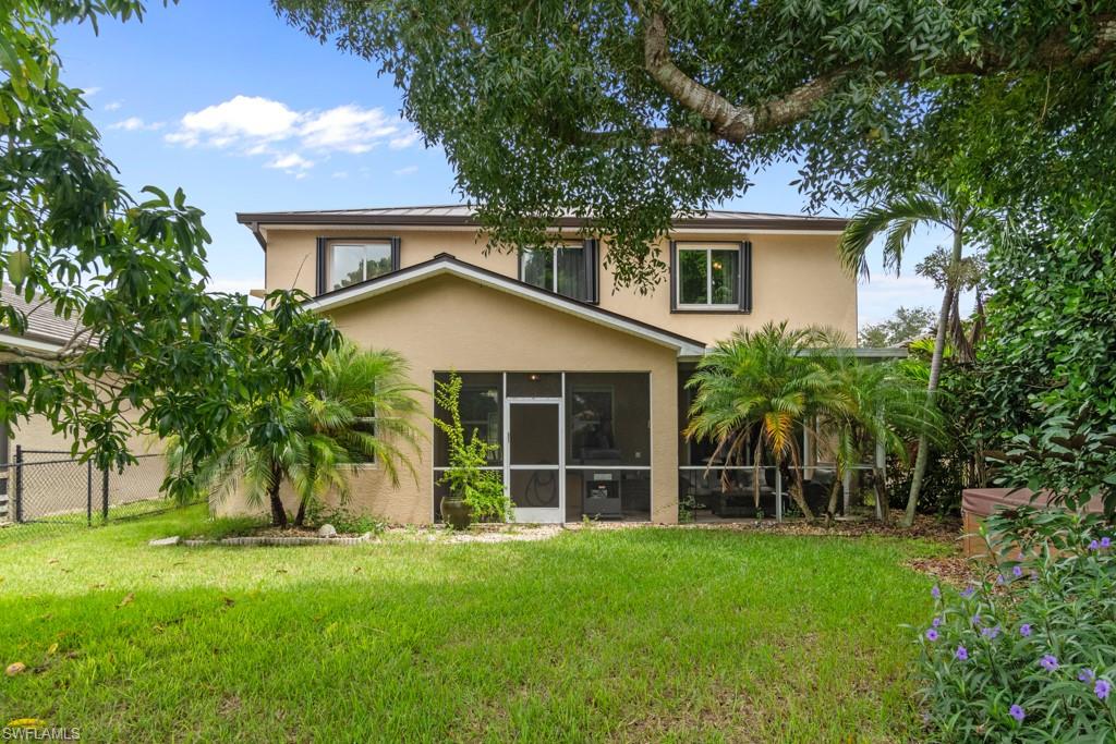 Spacious rear yard with a screened patio, mature trees, and landscaping