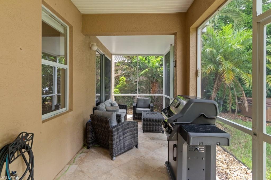 Screened patio featuring a tiled floor, stucco exterior, and lush tropical landscaping