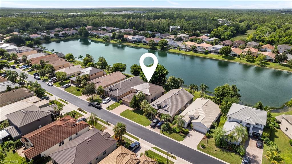 Lakefront property featuring a private driveway, mature landscaping, and multi-story construction