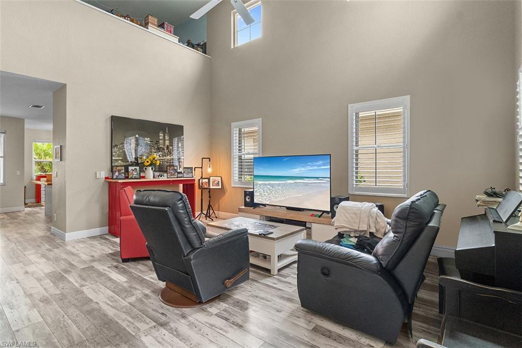 Open-concept living area featuring vaulted ceilings with skylights, wood-finish flooring throughout, and a media wall with built-in entertainment setup