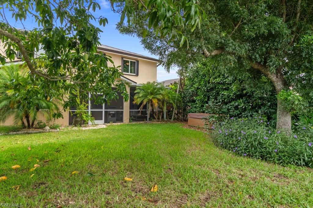 Expansive lawn with mature trees and established landscaping, featuring a screened-in patio