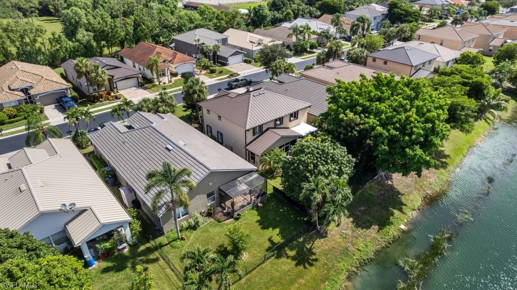 Residential property featuring a metal roof, screened enclosure, and adjacent water body