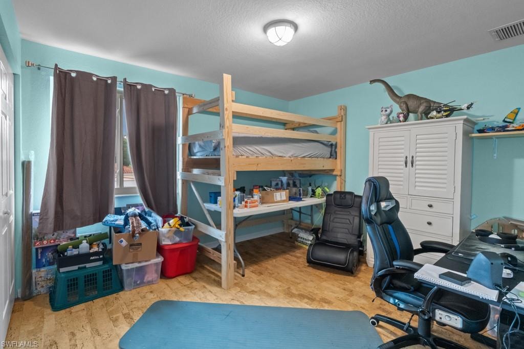 Spacious bedroom with turquoise walls and ceiling, wood-finish flooring, and abundant natural light from multiple windows