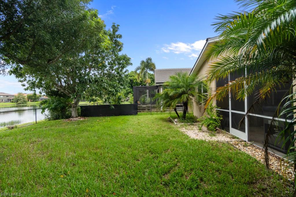 Expansive lawn featuring mature trees, screened patio, and a water feature