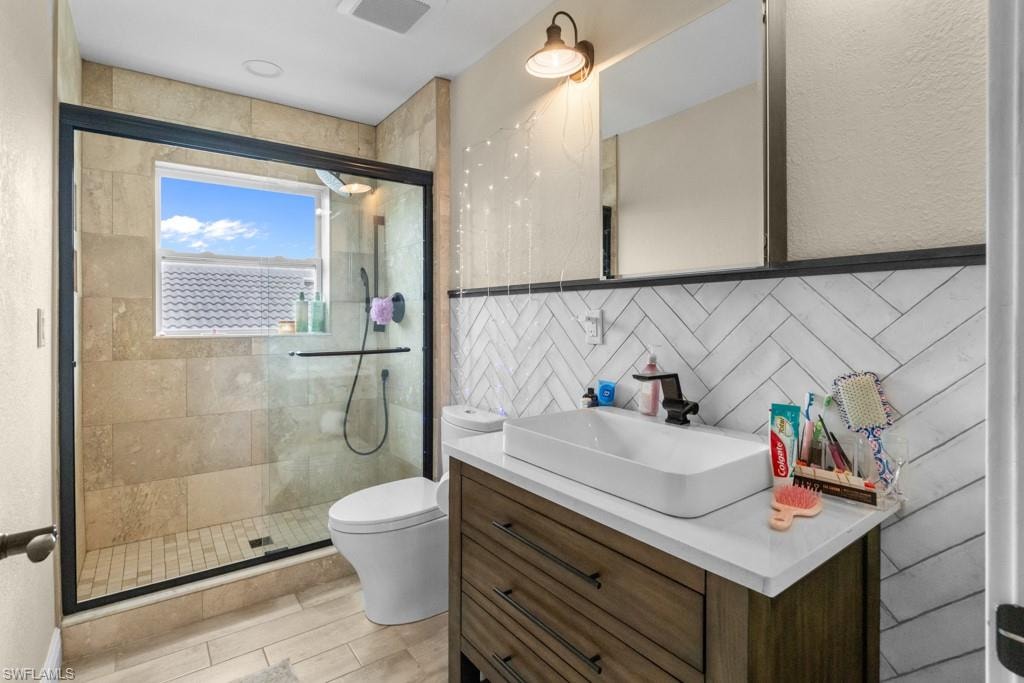 Walk-in shower with a glass enclosure, window, and tile surround