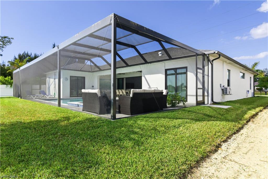 Back of house featuring a lanai, an outdoor living space, stucco siding, and a yard