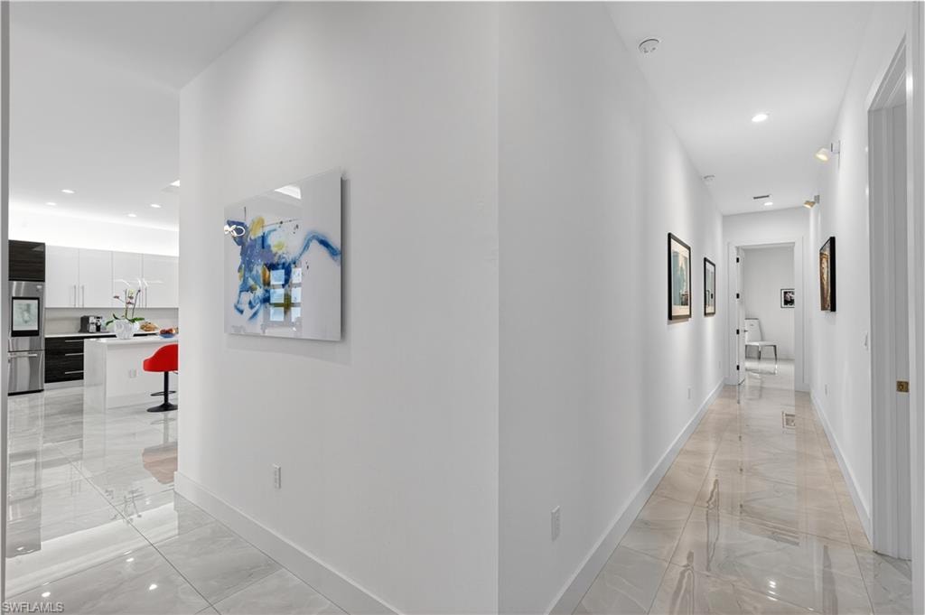 Hall with recessed lighting and light marble finish floors