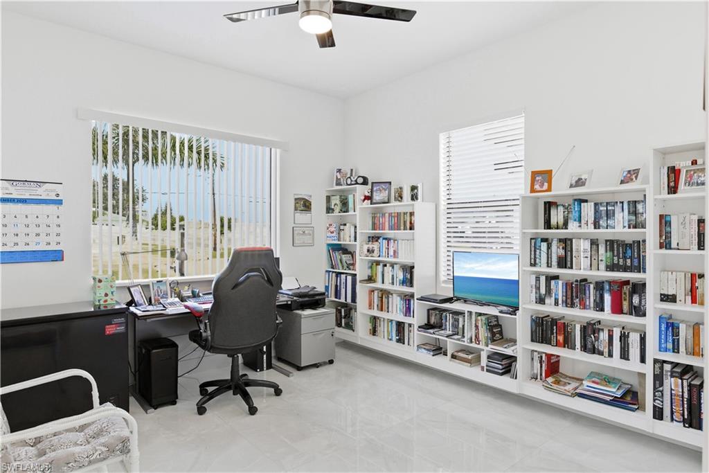Home office or guest bedroom with a ceiling fan and light marble finish flooring