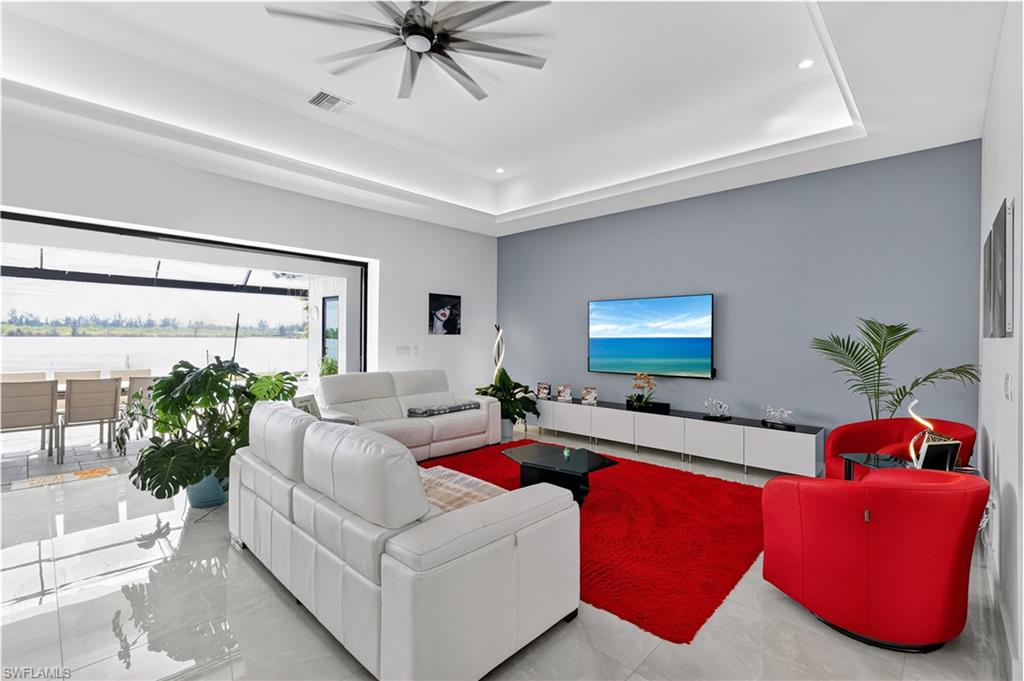 Living area featuring a raised ceiling, a ceiling fan, and recessed lighting