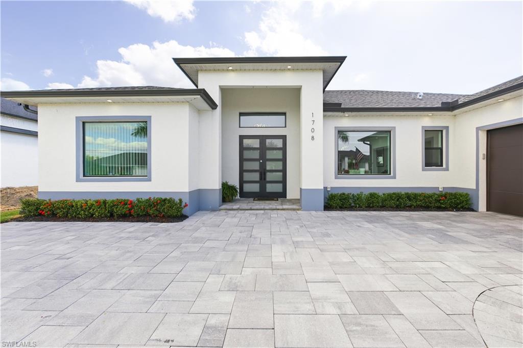 Property entrance featuring a garage, stucco siding, french doors, and decorative driveway