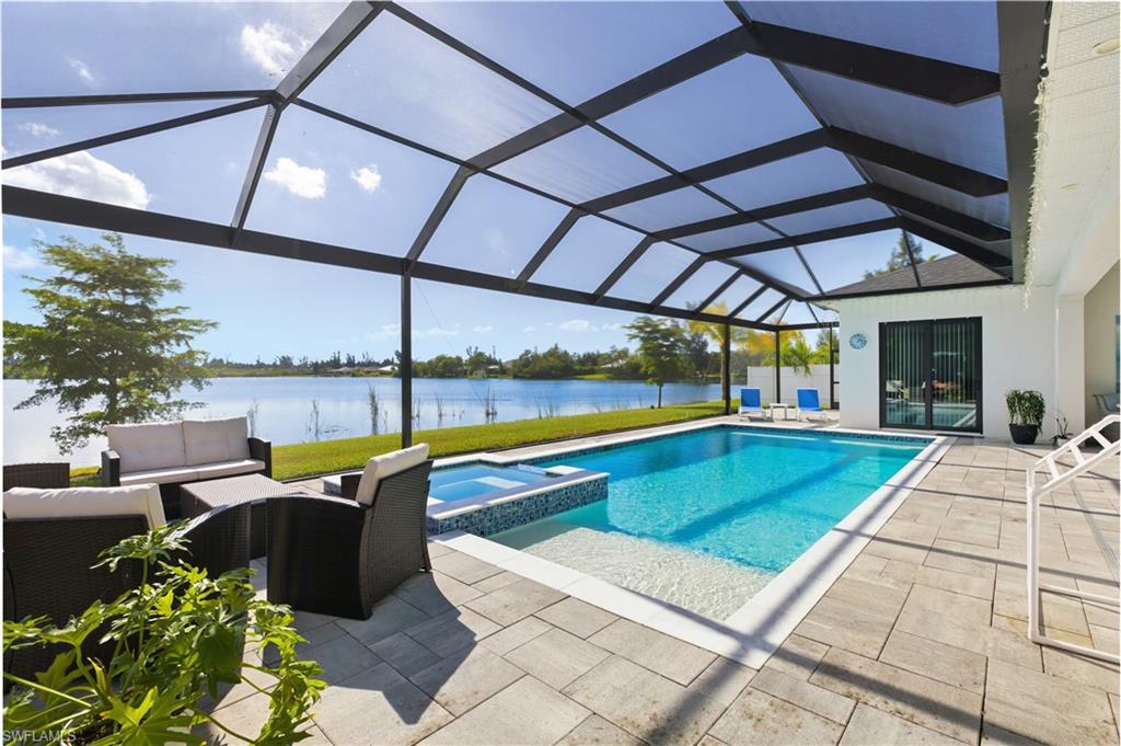 View of swimming pool featuring a sunroom, water view, a pool with connected hot tub, and screen enclosure