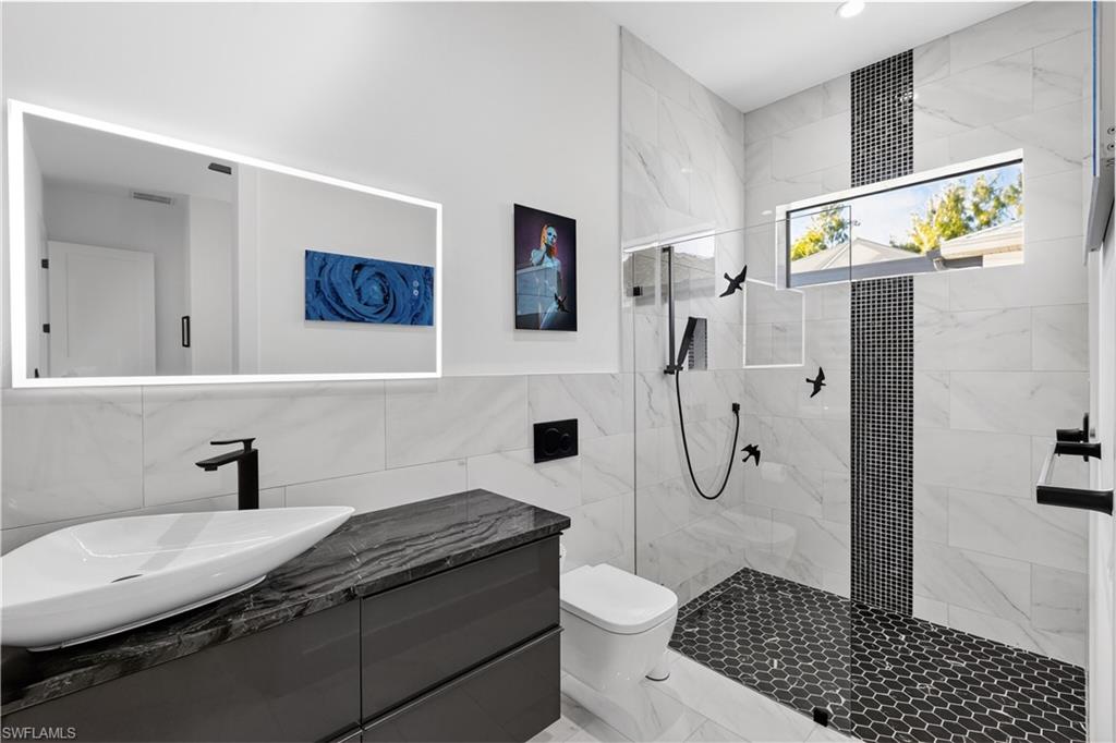 Full bath featuring tile walls, vanity, and a marble finish shower