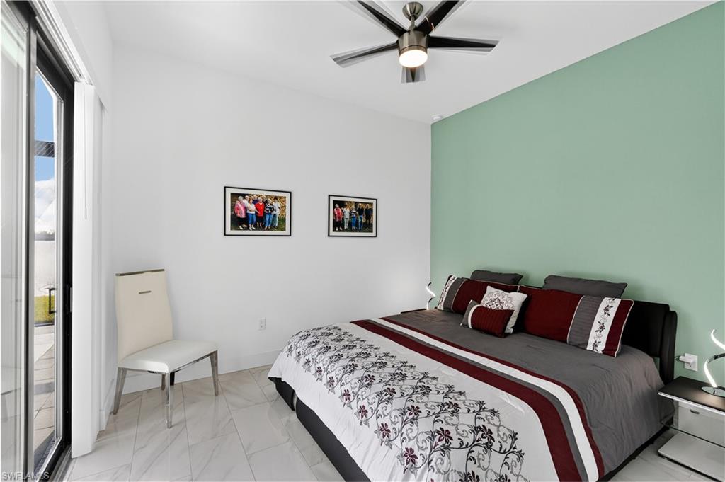 Guest bedroom with access to outside, a ceiling fan, and light marble finish floors