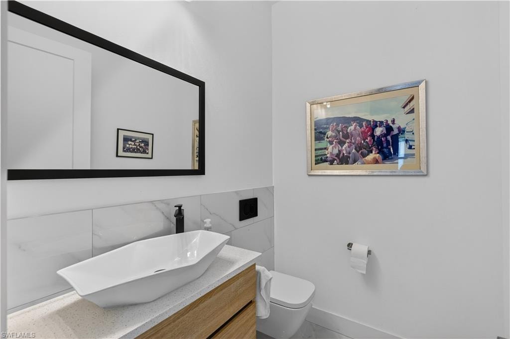 Half bathroom featuring vanity and tile walls