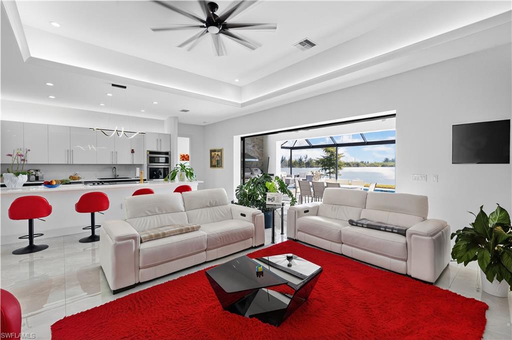 Living room with a raised ceiling, ceiling fan, and recessed lighting