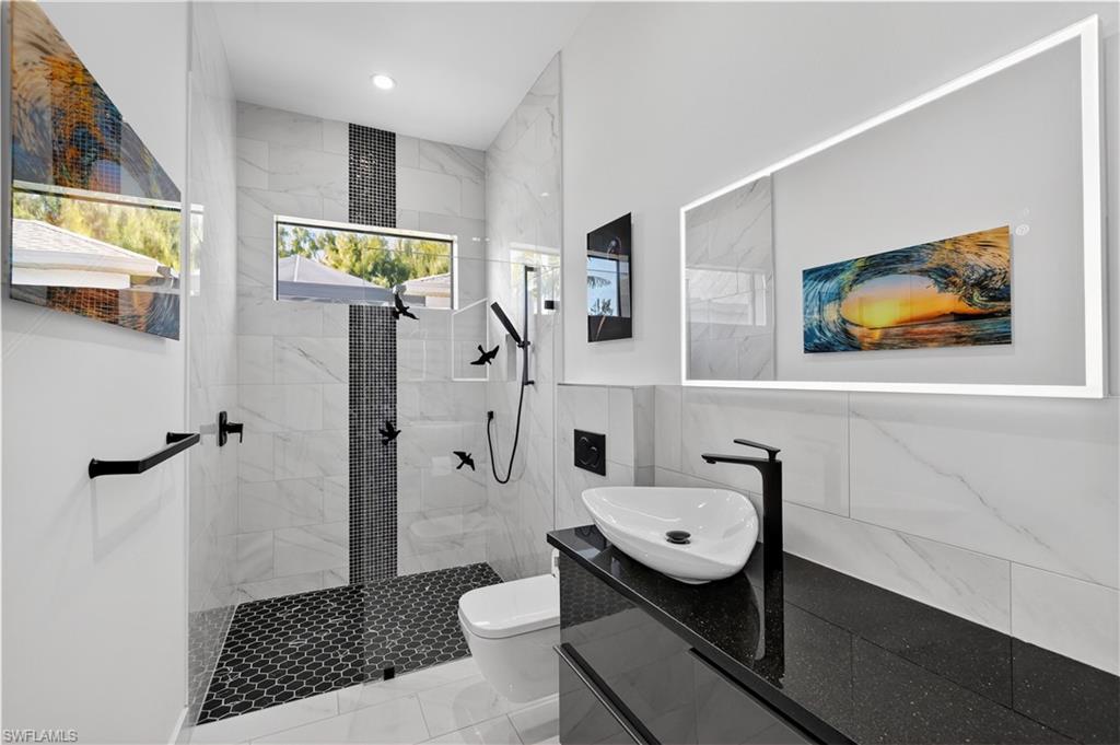 Full bath featuring a marble finish shower, vanity, and tile walls