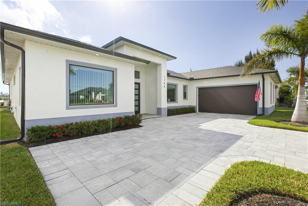 View of front of property featuring stucco siding, decorative driveway, and a garage