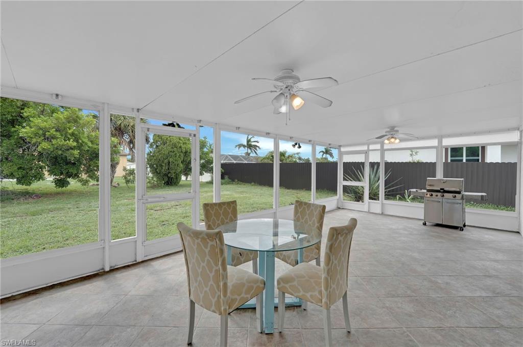 Screened outdoor living area with ceiling fans, a tile floor, and a white aluminum frame