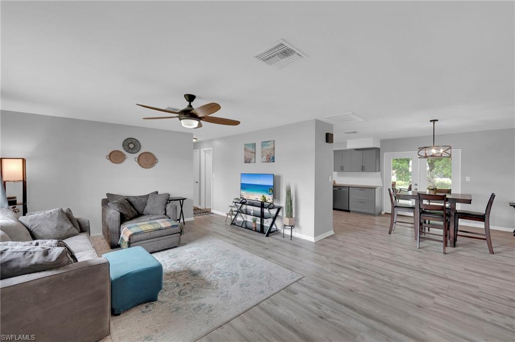Luxury laminate flooring throughout, ceiling fan with integrated lighting, recessed lighting, double doors providing outdoor access, and kitchen with gray cabinetry