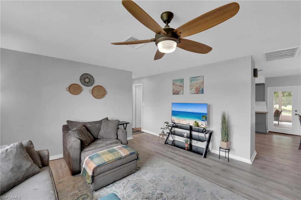 Living area featuring a ceiling fan with integrated lighting, light gray wall paint, and laminate flooring
