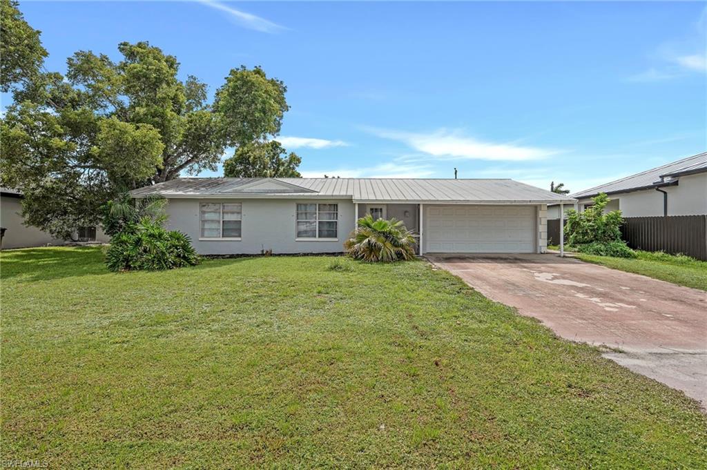Single-story residence featuring a metal roof, attached garage, and a carport
