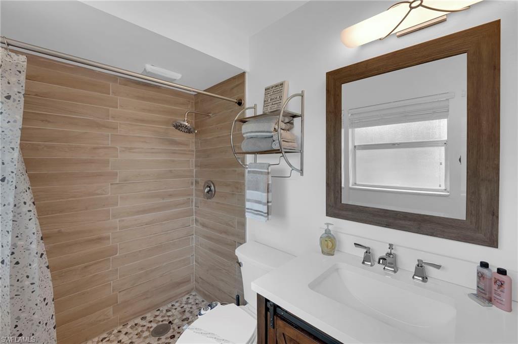 Walk-in shower with wood-finish tile, pebble floor, and rain showerhead