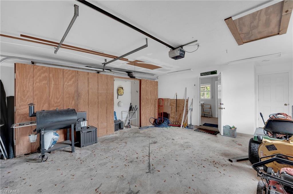 Attached garage featuring a concrete floor, white walls, and a wood-paneled storage wall