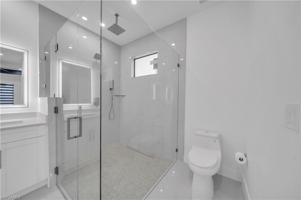 Glass-enclosed shower with hexagon mosaic tile flooring, rain shower head, and an additional shower wand