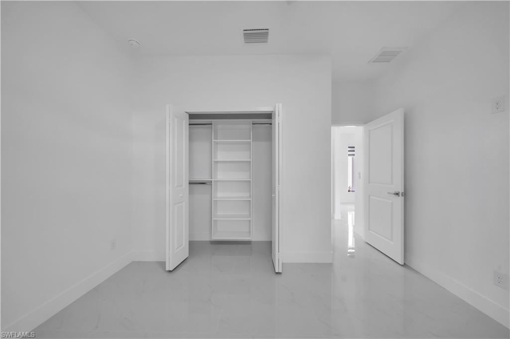 Crisp white walls, bright tile flooring, a closet with built-in shelving, and a paneled door