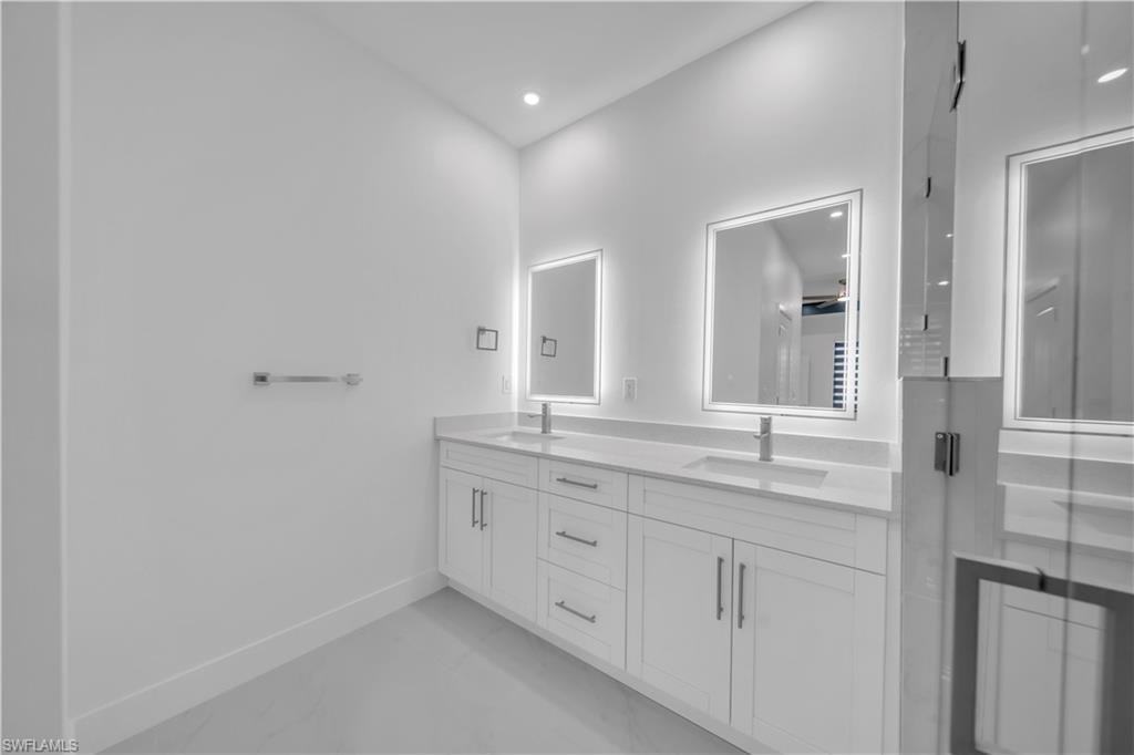 Dual vanity with white cabinetry, integrated sinks, chrome fixtures, and illuminated mirrors