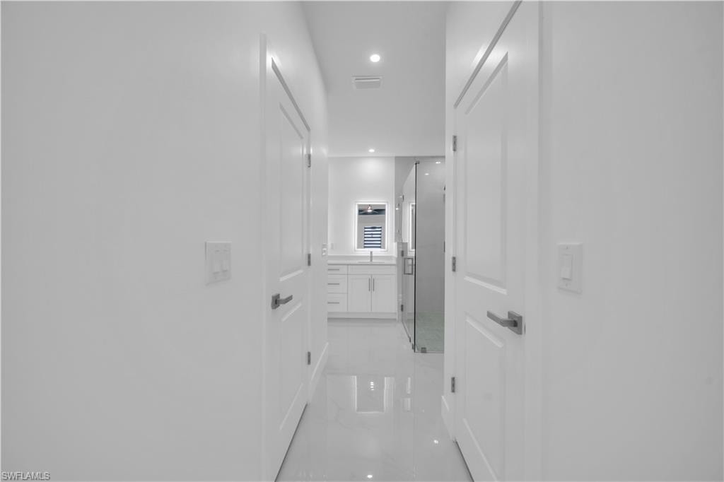 White interior doors with satin nickel hardware, recessed lighting, and polished tile flooring