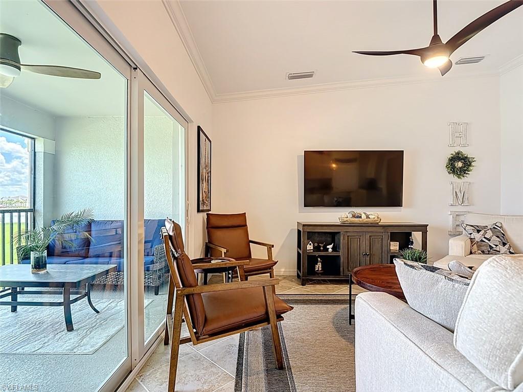 Living area featuring ceiling fan, crown molding, and light tile patterned flooring