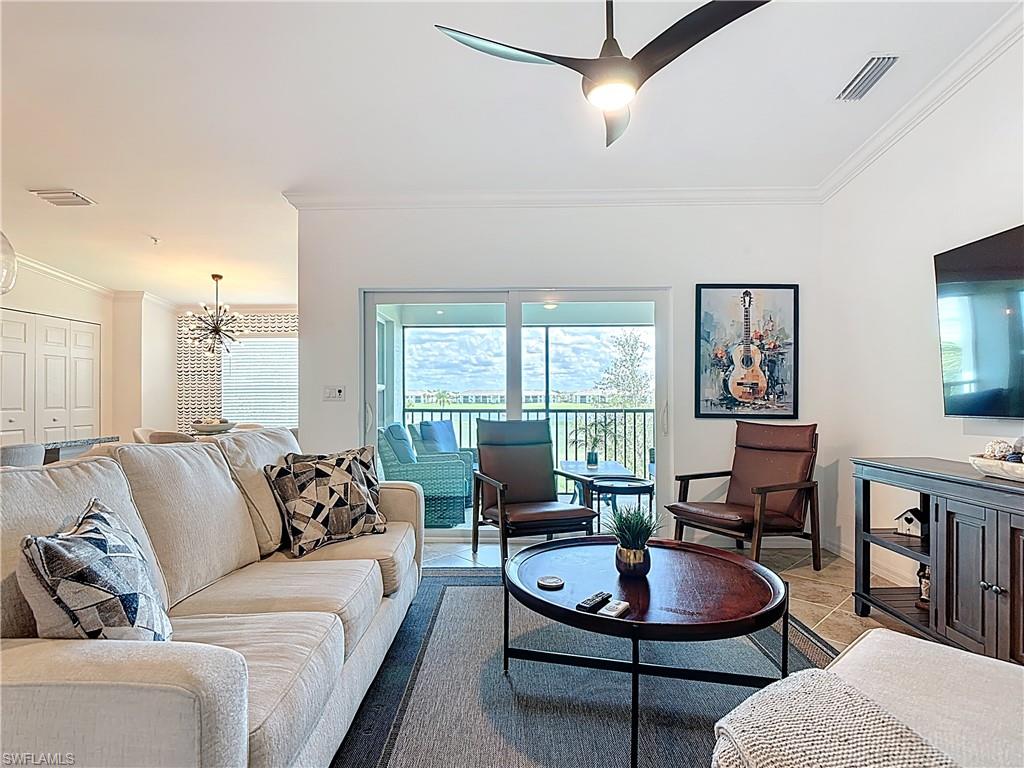 Living room with crown molding, a chandelier, ceiling fan, and light tile patterned flooring