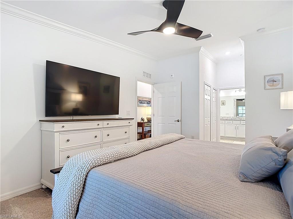 Bedroom featuring ornamental molding, light carpet, connected bathroom, and a ceiling fan