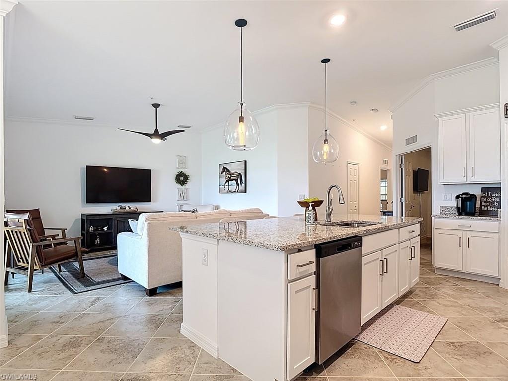 Kitchen featuring white cabinets, crown molding, open floor plan, light stone countertops, and dishwasher