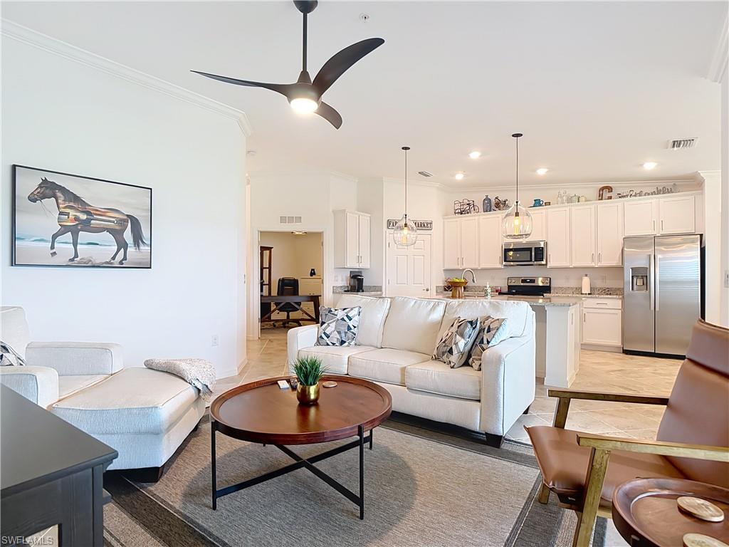 Living area featuring crown molding, a chandelier, ceiling fan, recessed lighting, and light tile patterned flooring