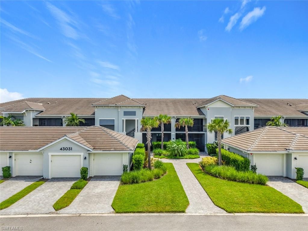 Traditional-style house featuring a tile roof, stucco siding, a residential view, and driveway