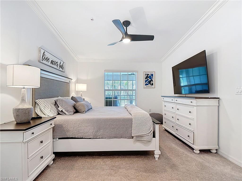 Bedroom with ornamental molding, light colored carpet, and ceiling fan