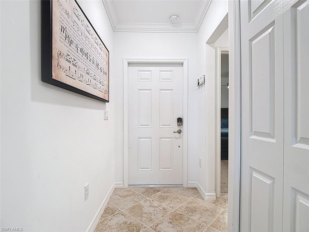 Doorway with baseboards and crown molding