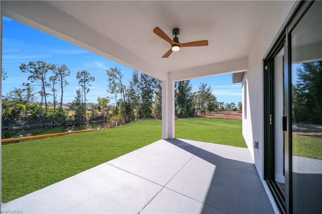 Covered patio with a wood-finish ceiling fan, concrete flooring, and sliding glass doors
