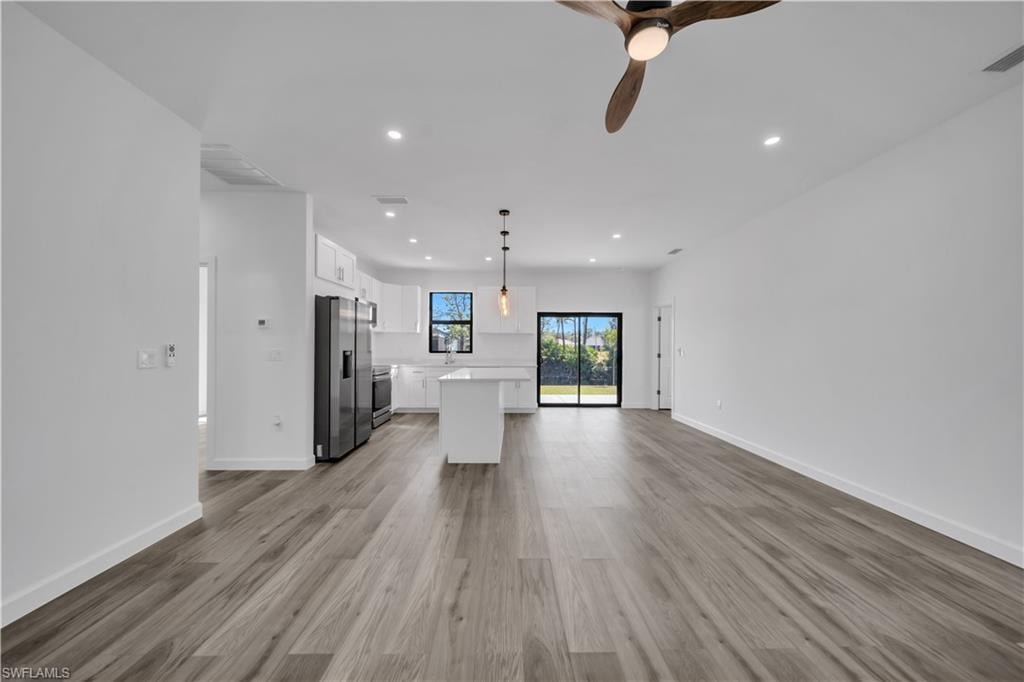 Open-concept living space with wood-finish flooring, recessed lighting, and a modern ceiling fan