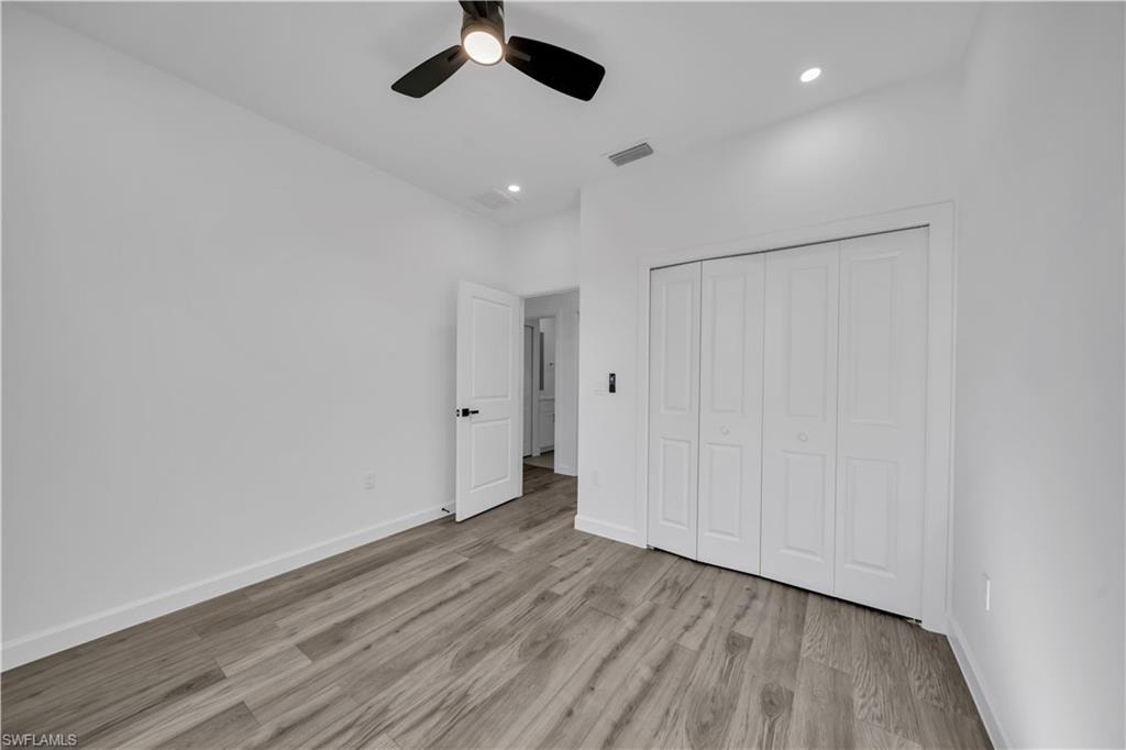 Wood-finish flooring, white walls, and a ceiling fan
