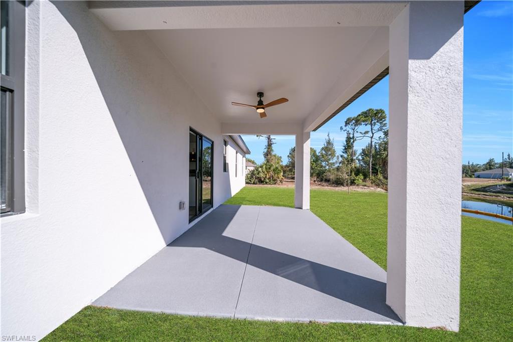 Covered patio with a ceiling fan, concrete flooring, and sliding glass doors
