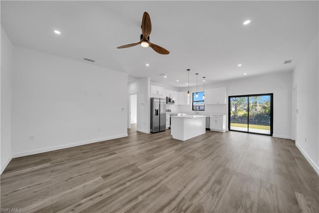 Open-concept living area featuring wide-plank wood-finish flooring, recessed ceiling lighting, and a bronze ceiling fan