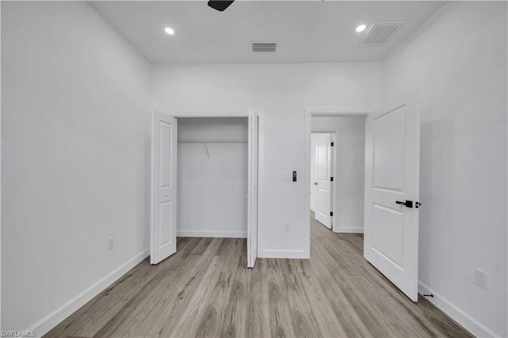 Wood-finish flooring, recessed lighting, and a bi-fold closet with wire shelving